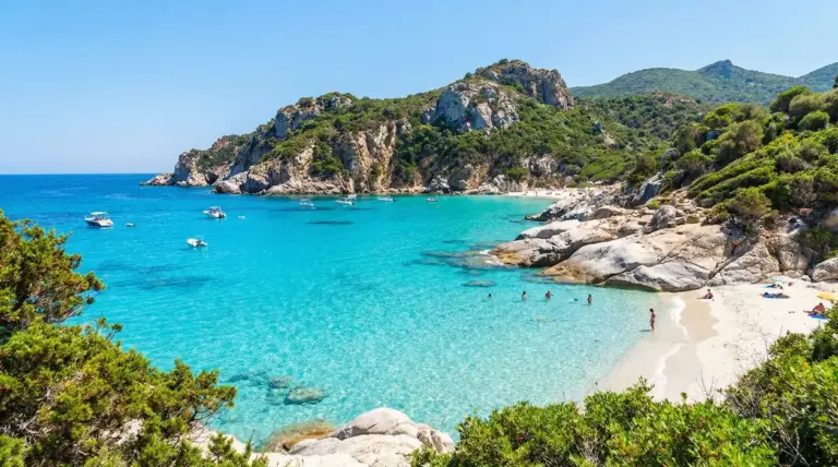 Cala con acqua cristallina, sabbia chiara e scogli tra la vegetazione nel Sud Italia