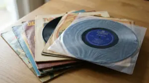 Pile di vinili vintage con copertine usurate e un disco in primo piano su un tavolo di legno